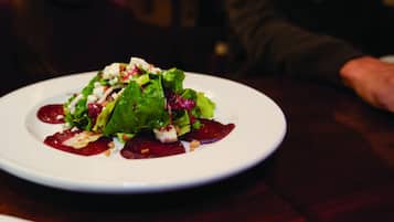 A plate of food with a salad, beetroot, and cheese on a white plate.