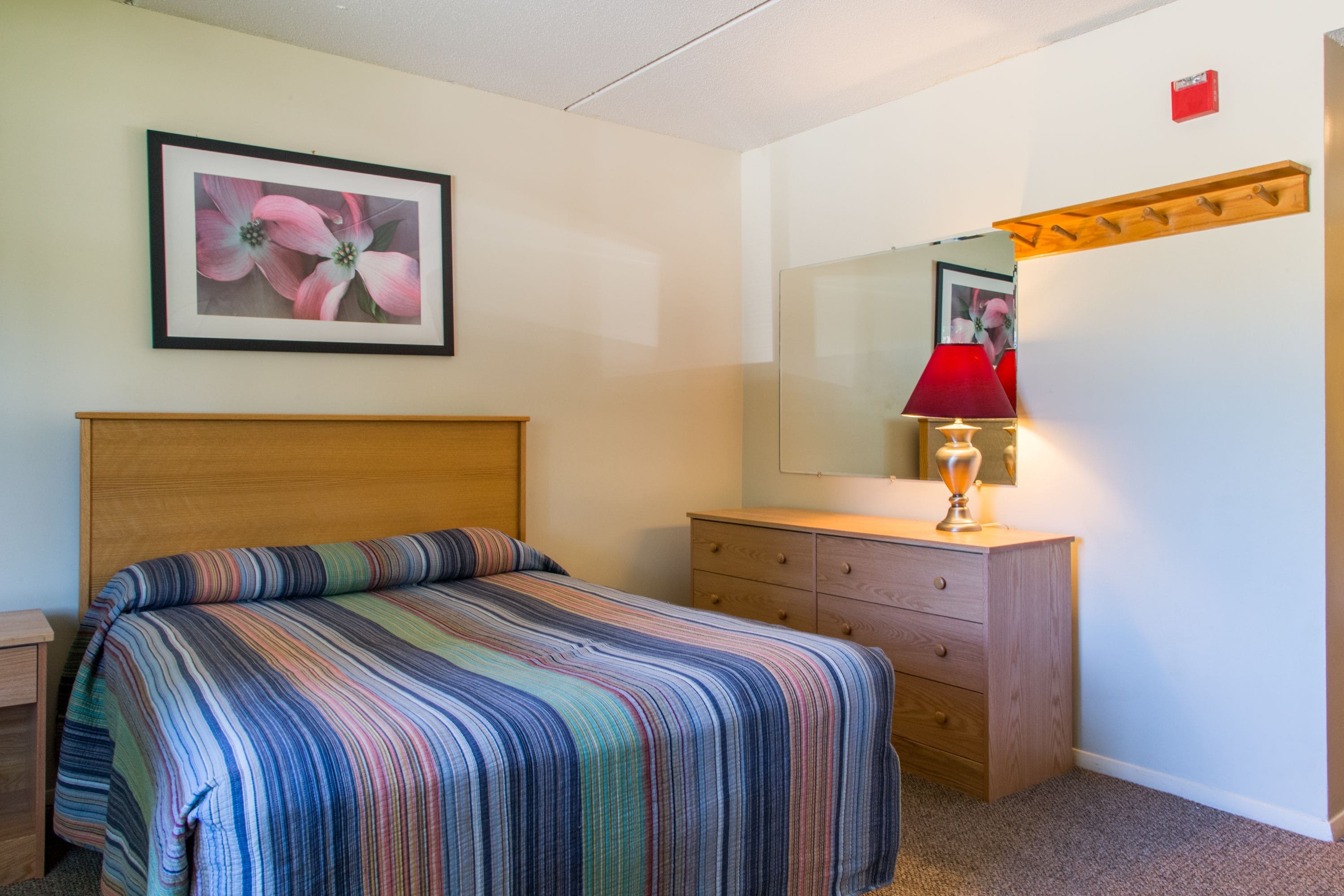 Un dormitorio con una cama, un aparador, un espejo y un cuadro en la pared.