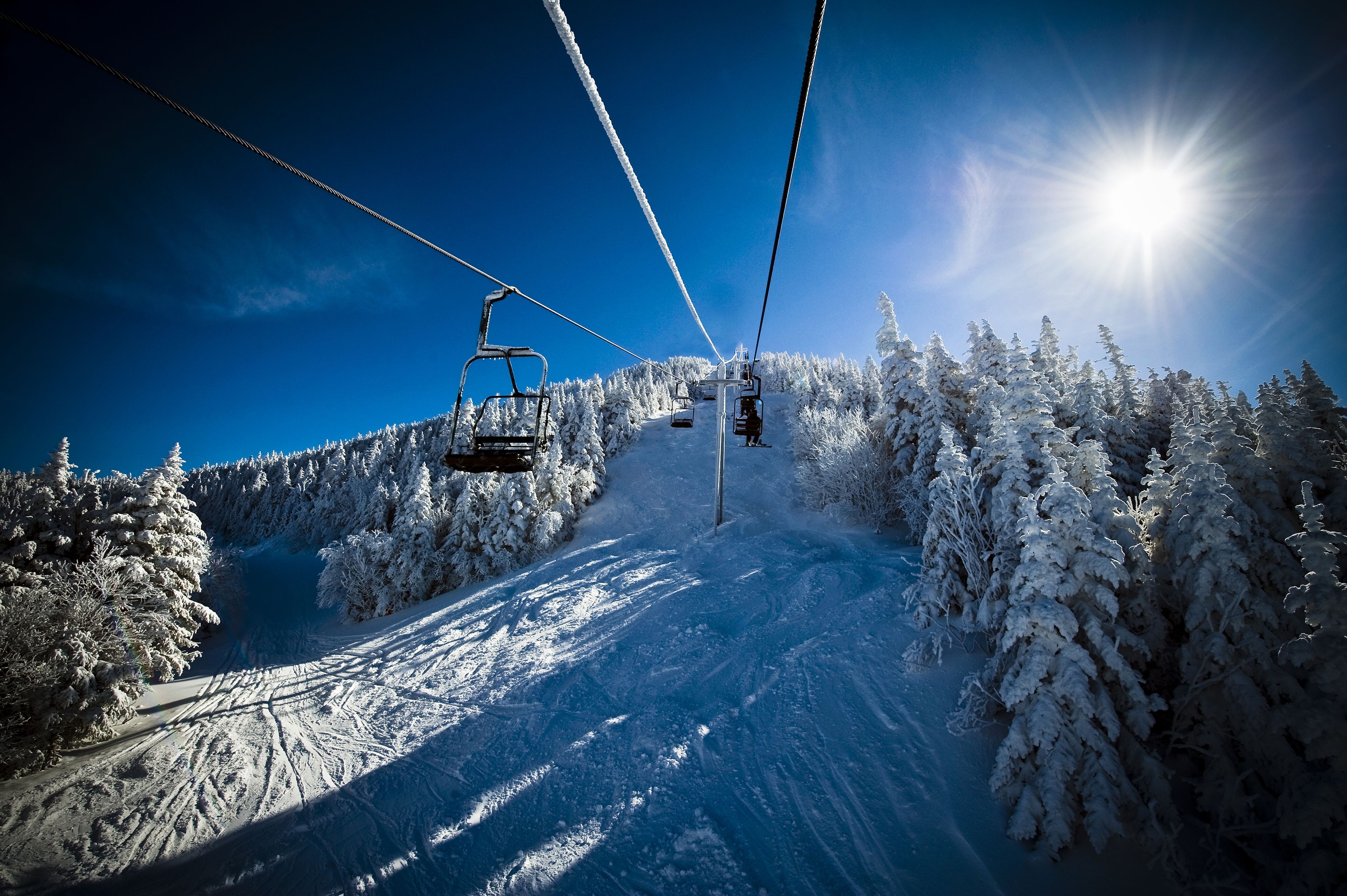 Eine Seilbahn auf einem verschneiten Berg unter blauem Himmel.