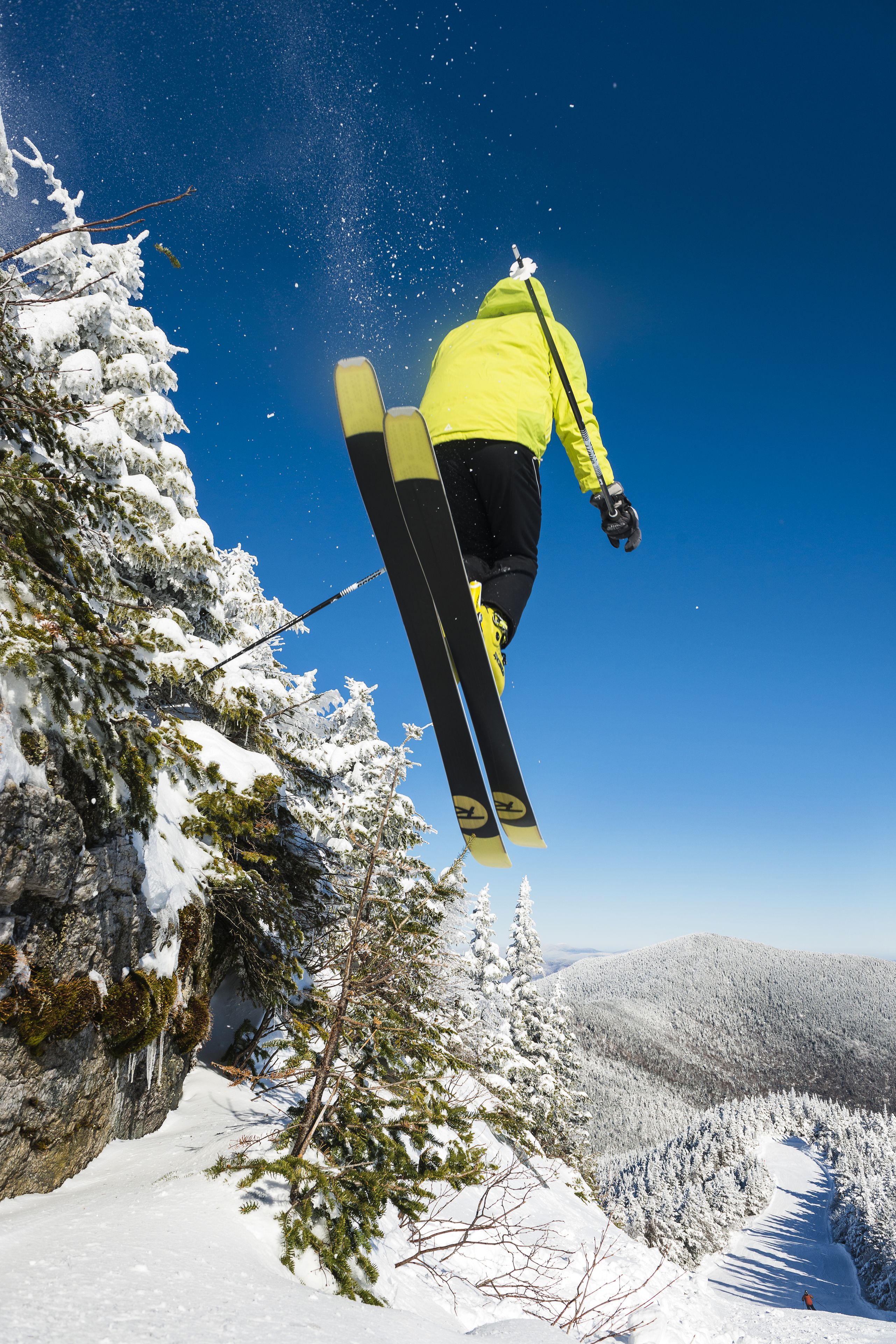 A skier mid-air performing a jump over a snowy mountain landscape.