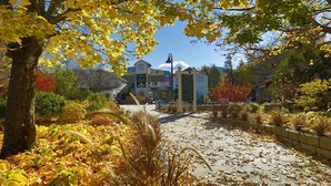 A pathway lined with autumn leaves leading to a building with a signboard. - Smugglers' Notch Resort (Jeffersonville)