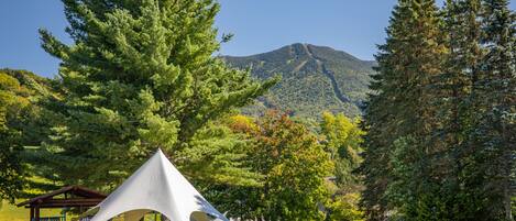 A campsite with a large white tent, picnic tables, and a wooden shelter.