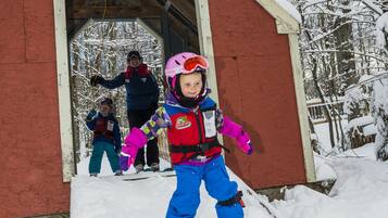 Een skihut met een rode gevel en een bord waarop staat 'Way Up High School'.
