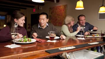 A group of people dining at a restaurant with wooden tables and yellow pendant lights.