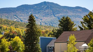 A residential area with a mountain in the background, a house with a brown roof, and a sign that reads "SMUGGLERS' NOTCH VERMONT". - Smugglers' Notch Resort (Jeffersonville)