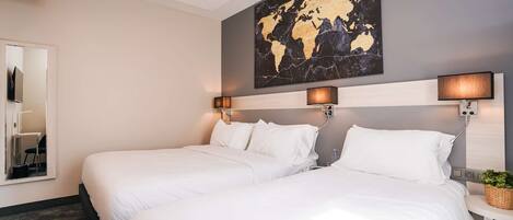 Una habitación de hotel con dos camas, un cuadro con un mapa mundial en la pared y lámparas de noche.