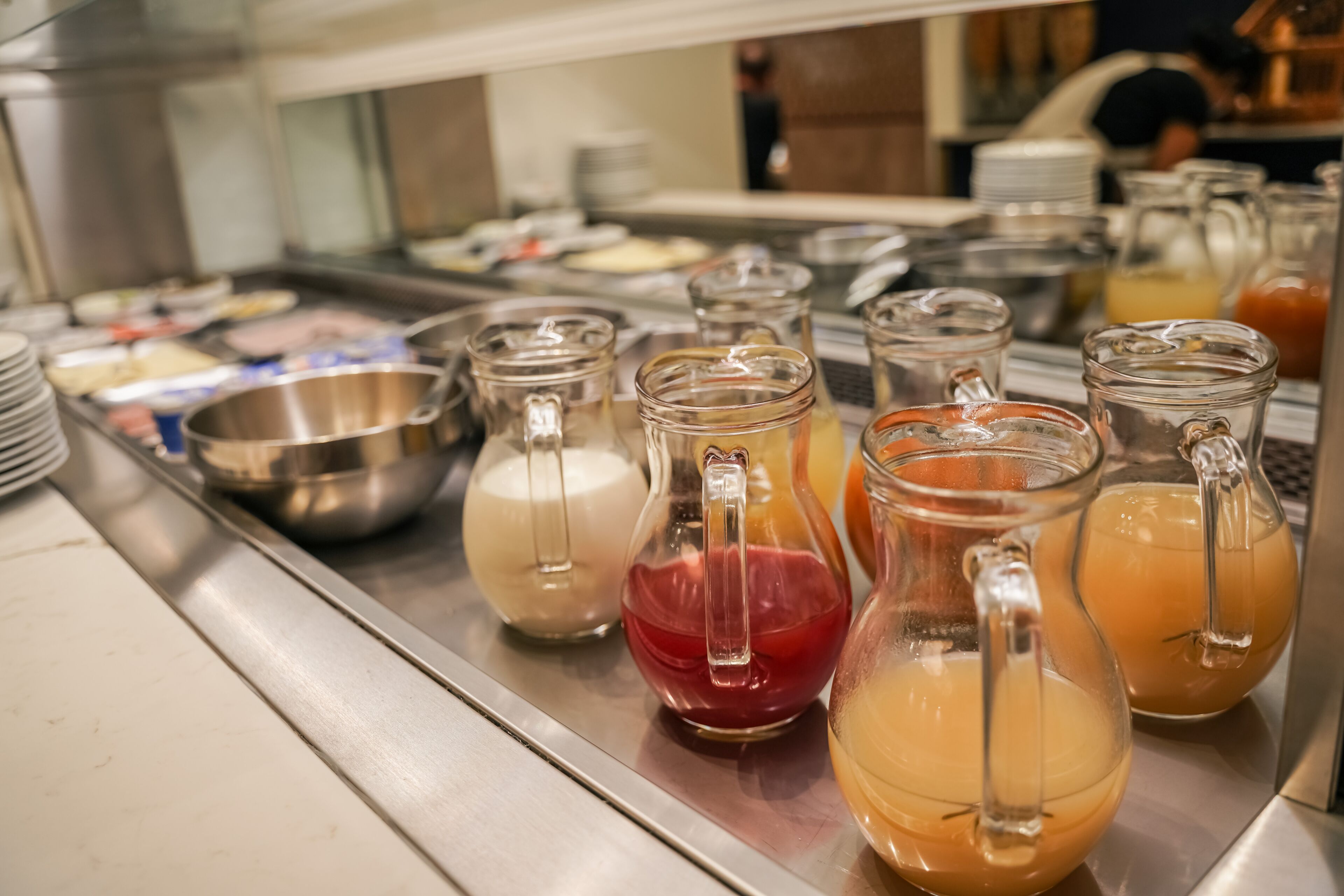 A buffet area with various food items and beverages in glass containers.