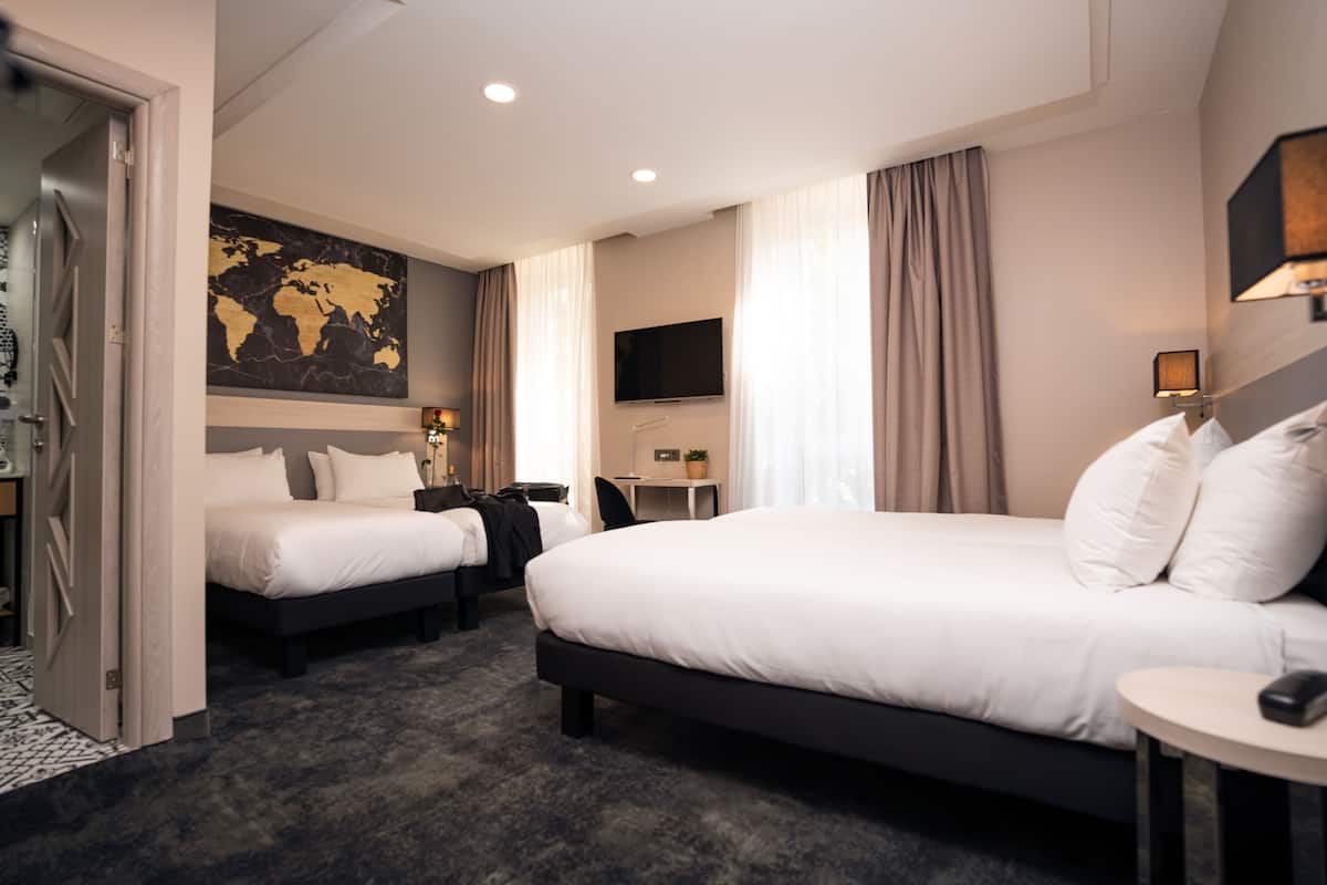 Una habitación de hotel con dos camas, un escritorio, un televisor y un mapa mundial en la pared.