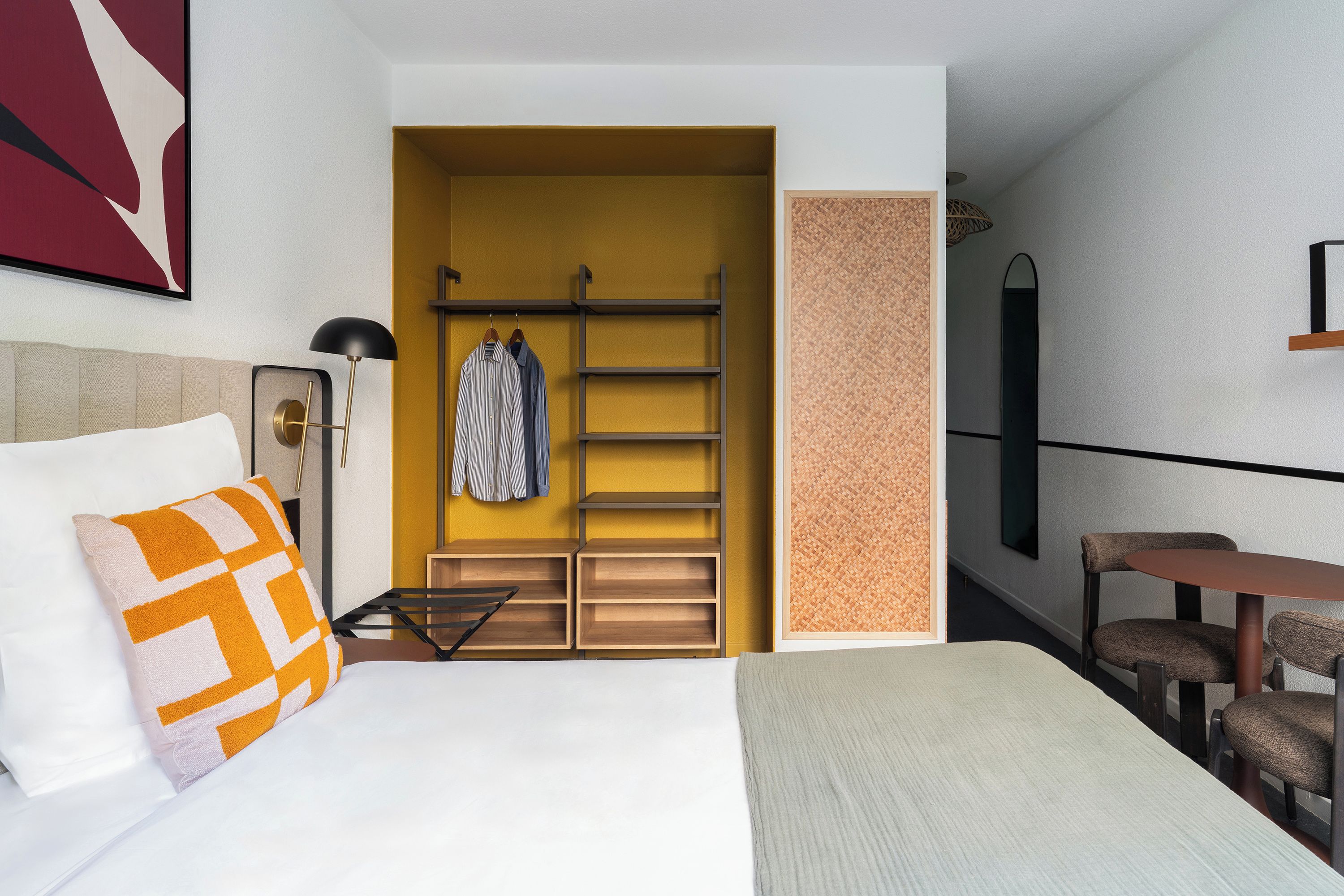 Una camera d'albergo con un letto, una scrivania, una sedia, un armadio e un appendiabiti.