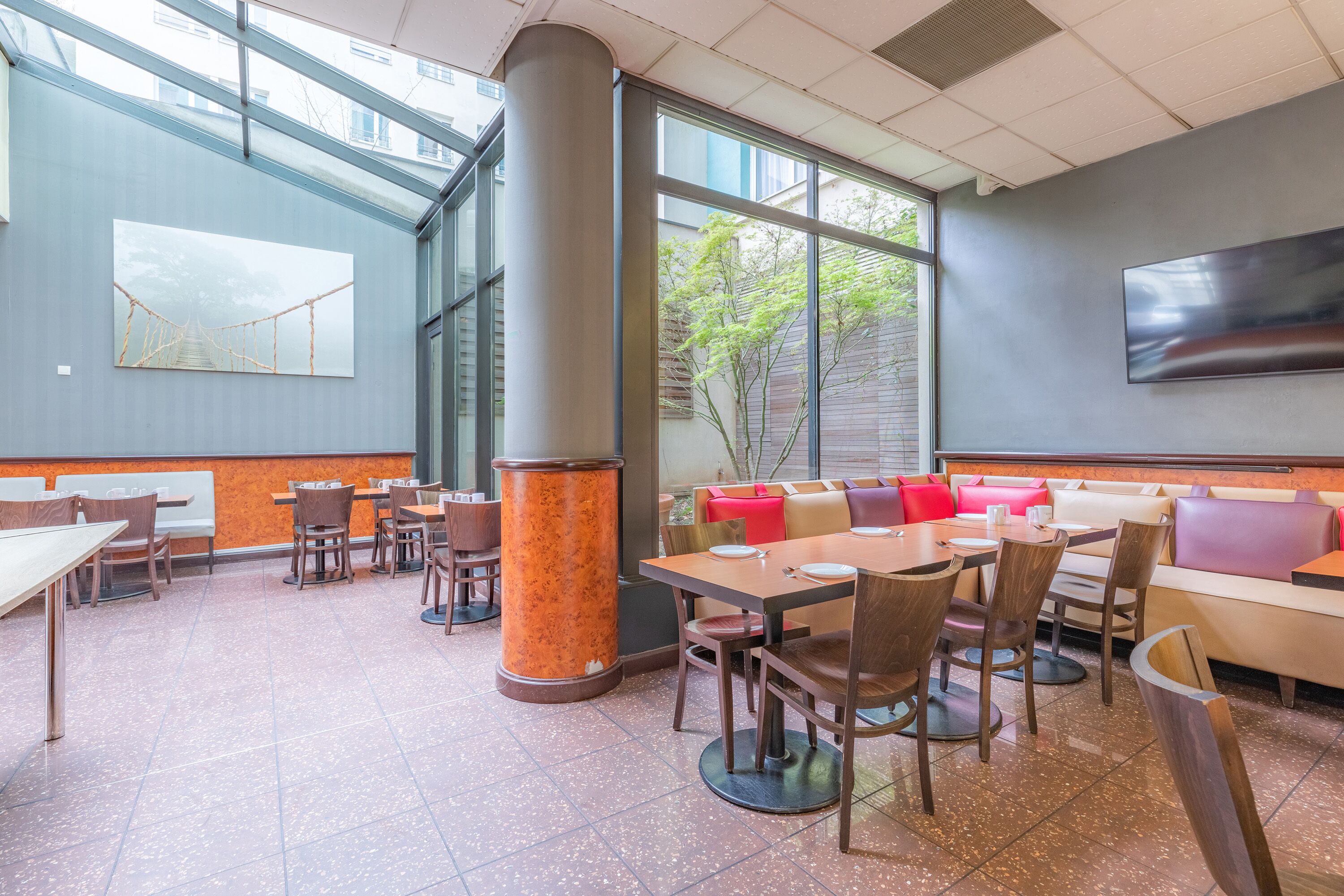 A modern restaurant with high ceilings, large windows, and a mix of seating options including tables and booths.