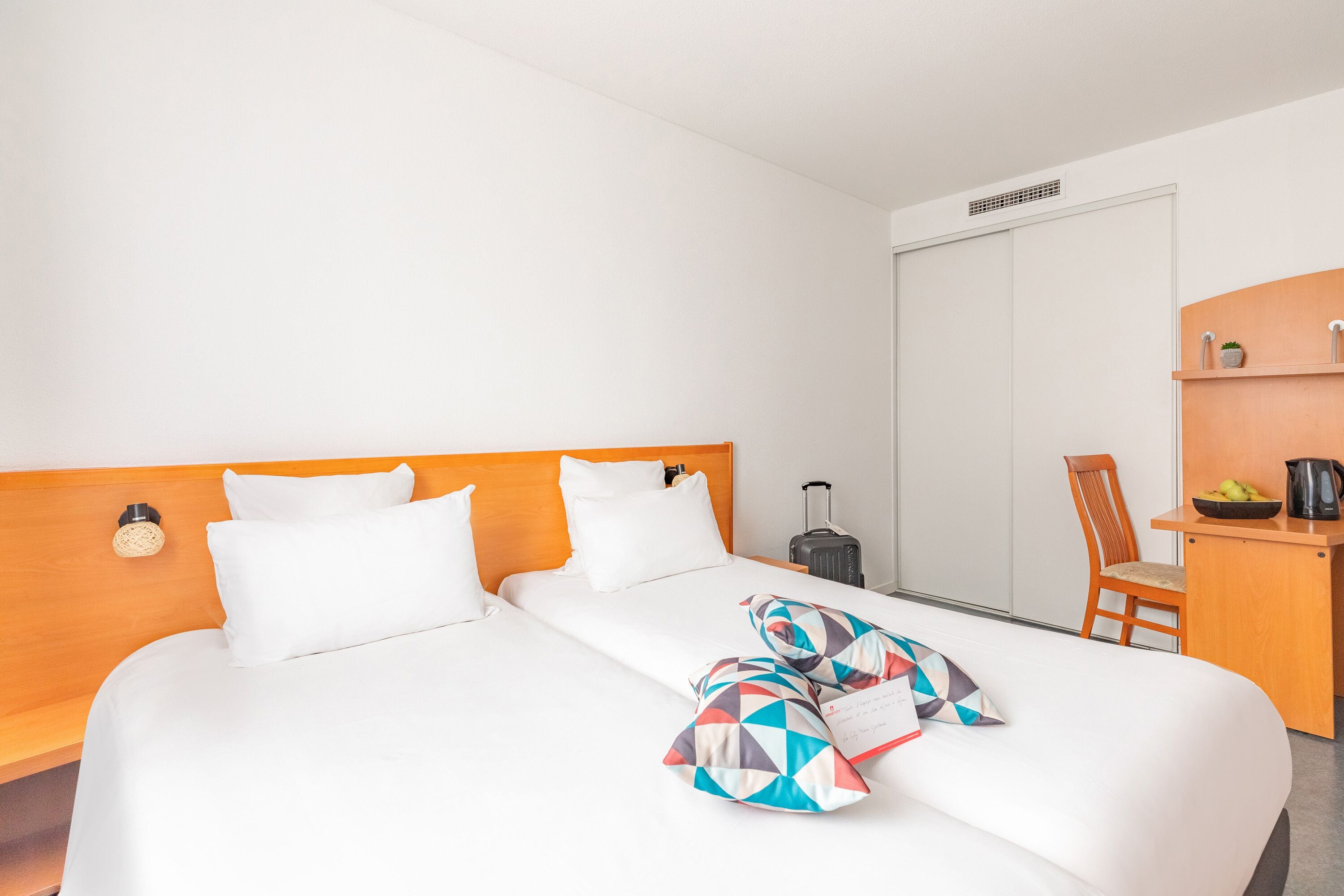 A hotel room with a bed, a desk, a chair, and a small kitchenette.