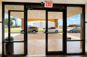 A building entrance with a clear view of parked cars outside.