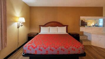 A hotel room with a bed, a nightstand, a lamp, and a mirror.