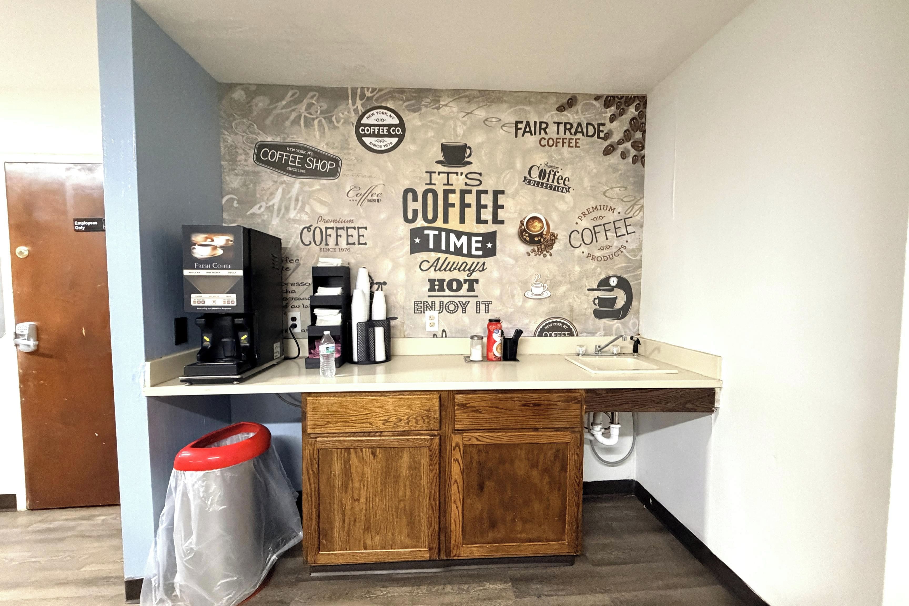 A coffee station with a coffee machine, a water bottle, and a trash bin.