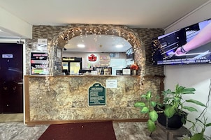Un mostrador de recepción de hotel con un letrero sobre la política de mascotas, una pantalla de televisión y un letrero que dice 'Fresh Food'.
