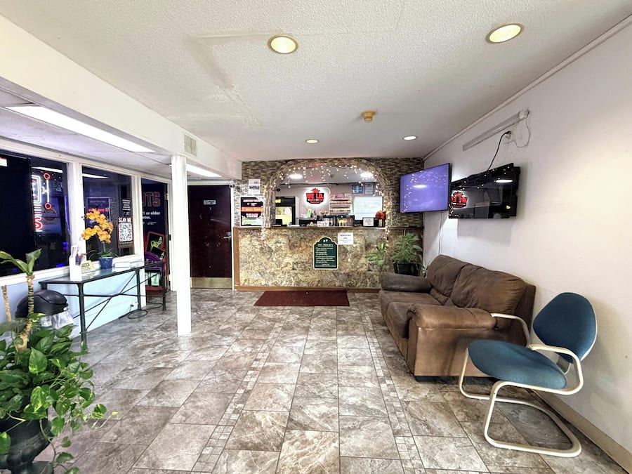 A reception area with a counter, seating, a television, and a wall-mounted screen.