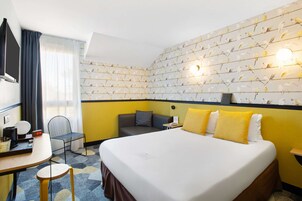 Una habitación de hotel con una cama grande, un escritorio con silla, una mesita y un televisor.