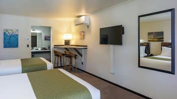 Een hotelkamer met twee bedden, een bureau met stoel, een televisie en een spiegel.