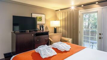 Ein Hotelzimmer mit Bett, Fernseher, Schreibtisch mit Lampe und Stuhl.