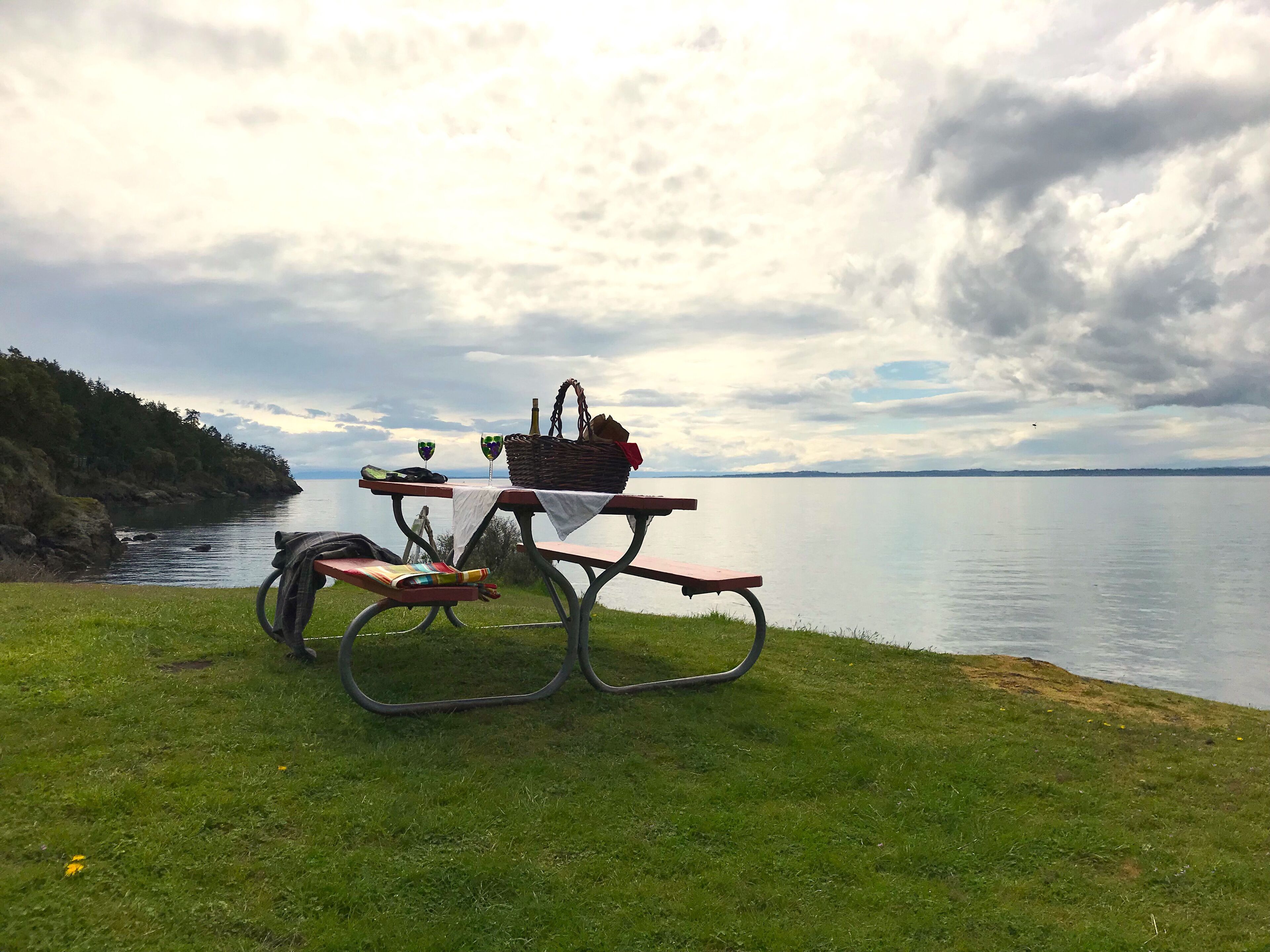 Ein Picknick am Seeufer mit Tisch, Stühlen und Picknickutensilien.