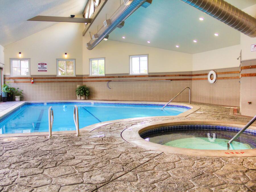 An indoor swimming pool with a stone floor, a hot tub labeled "STEP," and a notice sign on the wall.