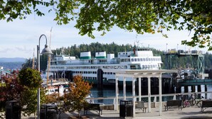 A waterfront promenade with benches, a gazebo, and a large white boat docked at a pier. - Earthbox Inn & Spa (Friday Harbor)