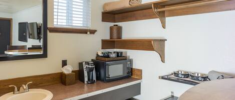 A compact kitchenette with a sink, microwave, coffee maker, and a small refrigerator.