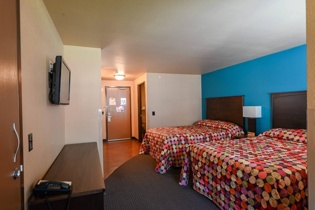 A hotel room with two beds, a desk, a telephone, and a television.