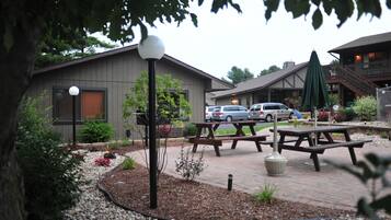 A building with a patio area, picnic tables, and a carport.