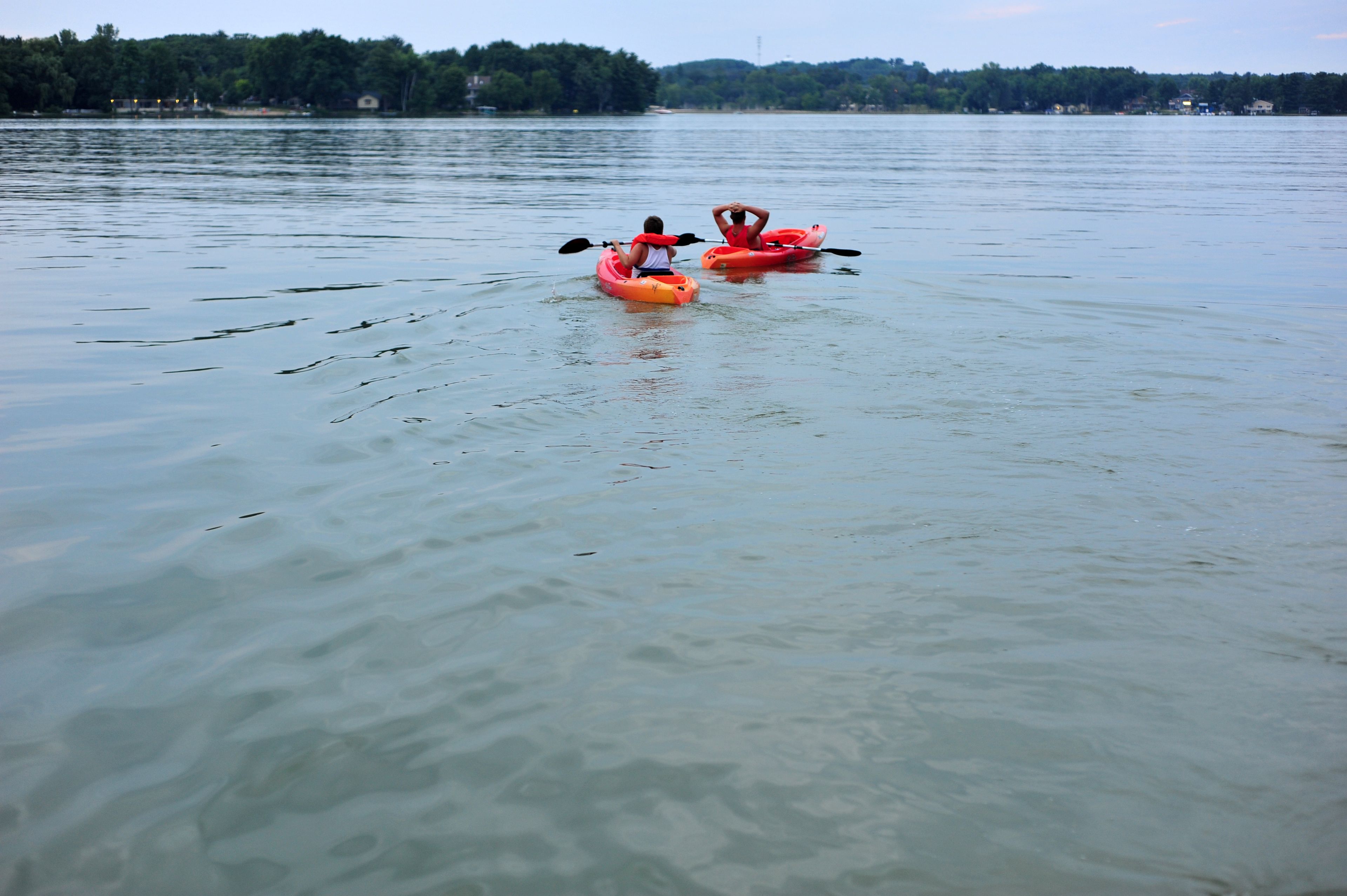 Two kayaks on a calm lake with a forested shoreline in the background.