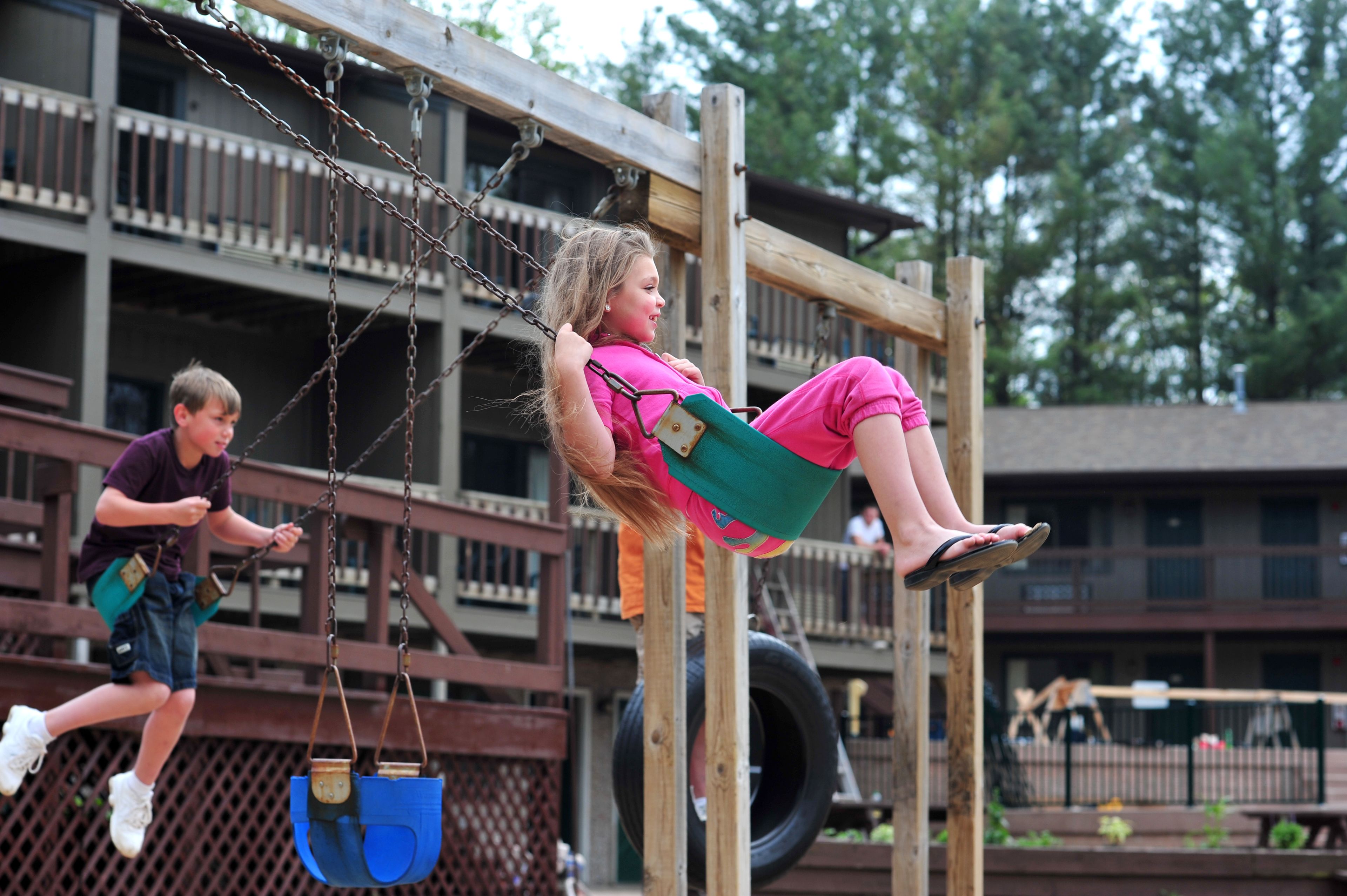 A wooden swing set with a tire swing and a child swinging.