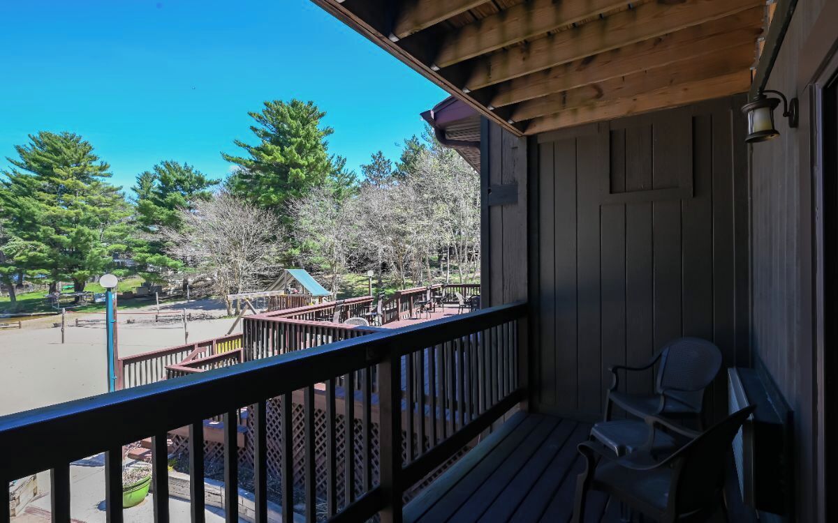 A wooden balcony with a view of a park and trees.