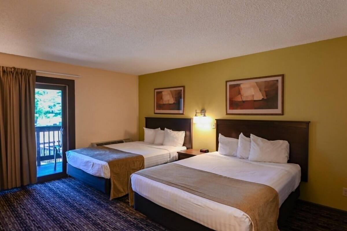 A hotel room with two beds, a balcony, and two framed pictures on the wall.