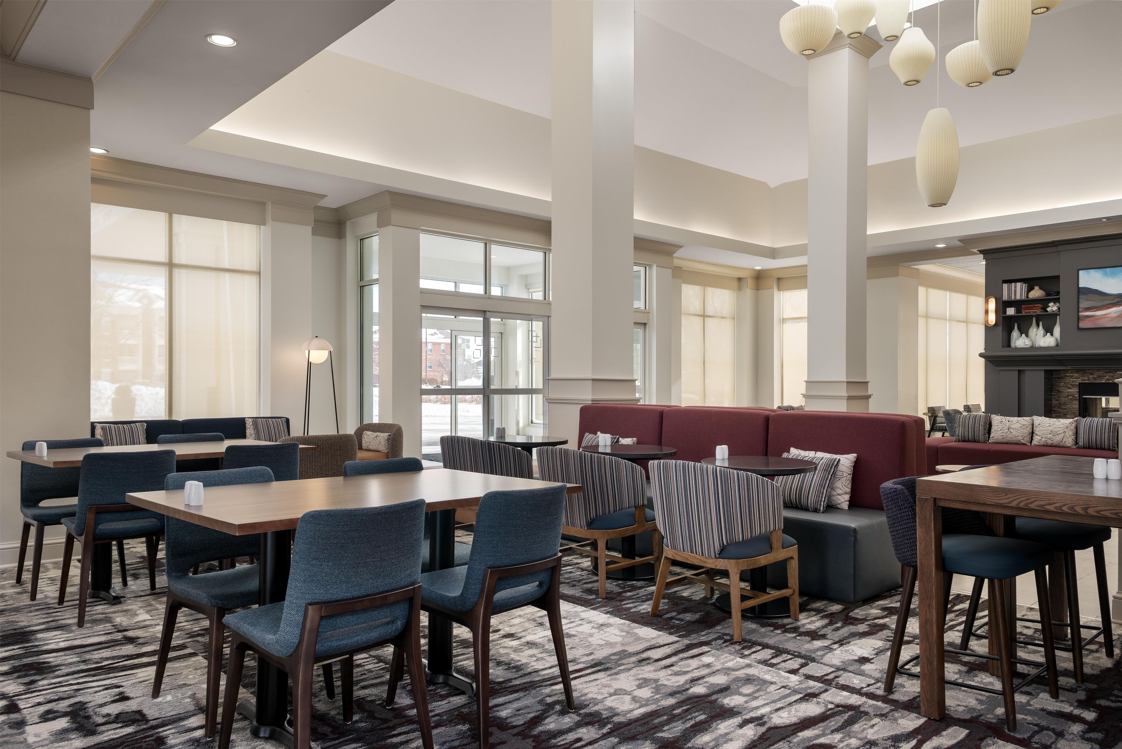A hotel lobby with seating areas, tables, and a fireplace.