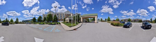 A parking lot with handicap-accessible spaces, a covered entrance, and a building with a green roof. - Hilton Garden Inn Indianapolis/Carmel (Carmel)