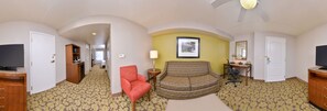 A hotel room with a sofa, a red chair, a desk with a computer, a television, and a bed. - Hilton Garden Inn Indianapolis/Carmel (Carmel)