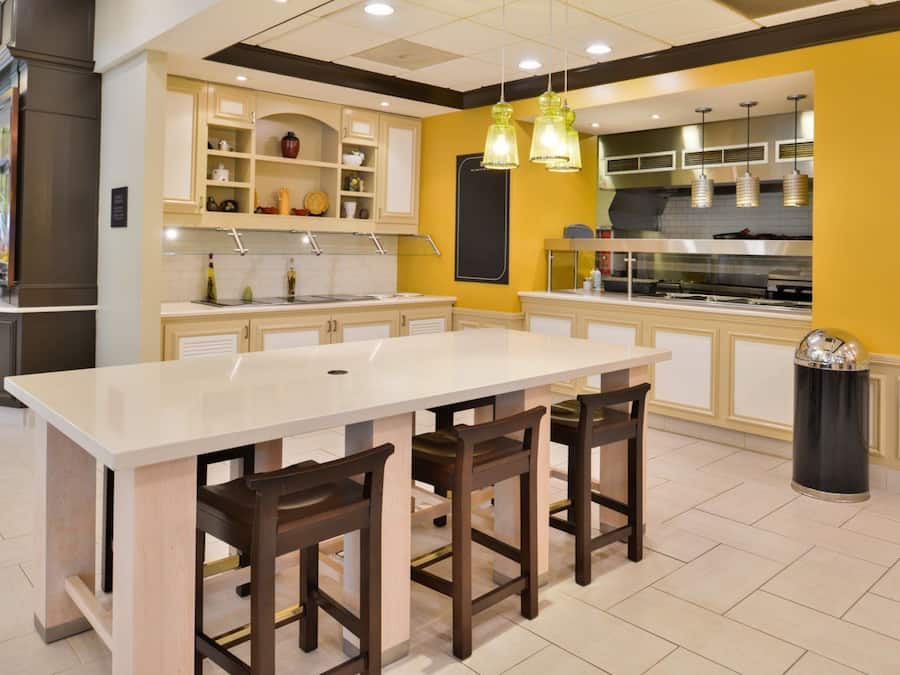 Une cuisine moderne dotée d’un îlot central, de tabourets de bar et de luminaires suspendus.