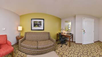 Una habitación de hotel con escritorio, silla, televisor y sofá.