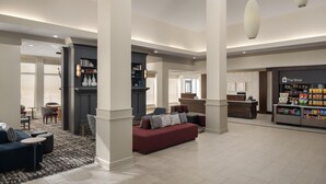 A spacious lobby with a reception desk, a seating area with a red sofa, and a snack bar.