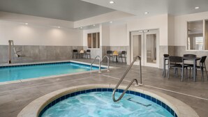A swimming pool with a hot tub, seating area, and a door leading to another room.