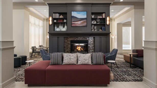 A modern living room with a fireplace, a red sofa, and a bookshelf with decorative items.