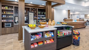 En hotellobby med en bemannad reception, en avdelning där man själv kan plocka fram snacks, en mikrovågsugn och ett urval av förpackade varor.
