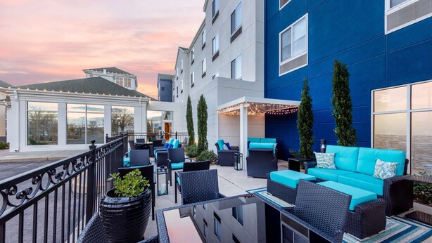 En takterrass med utomhusmöbler, en vit pergola och en blå fasad.