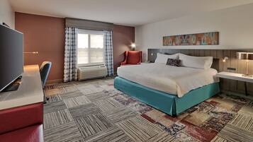 Hotelkamer met een groot bed, een bureau met stoel, een televisie en een raam met gordijnen.
