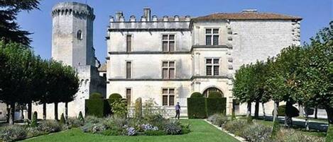 A historic building with a tower, multiple windows, and a well-maintained garden.