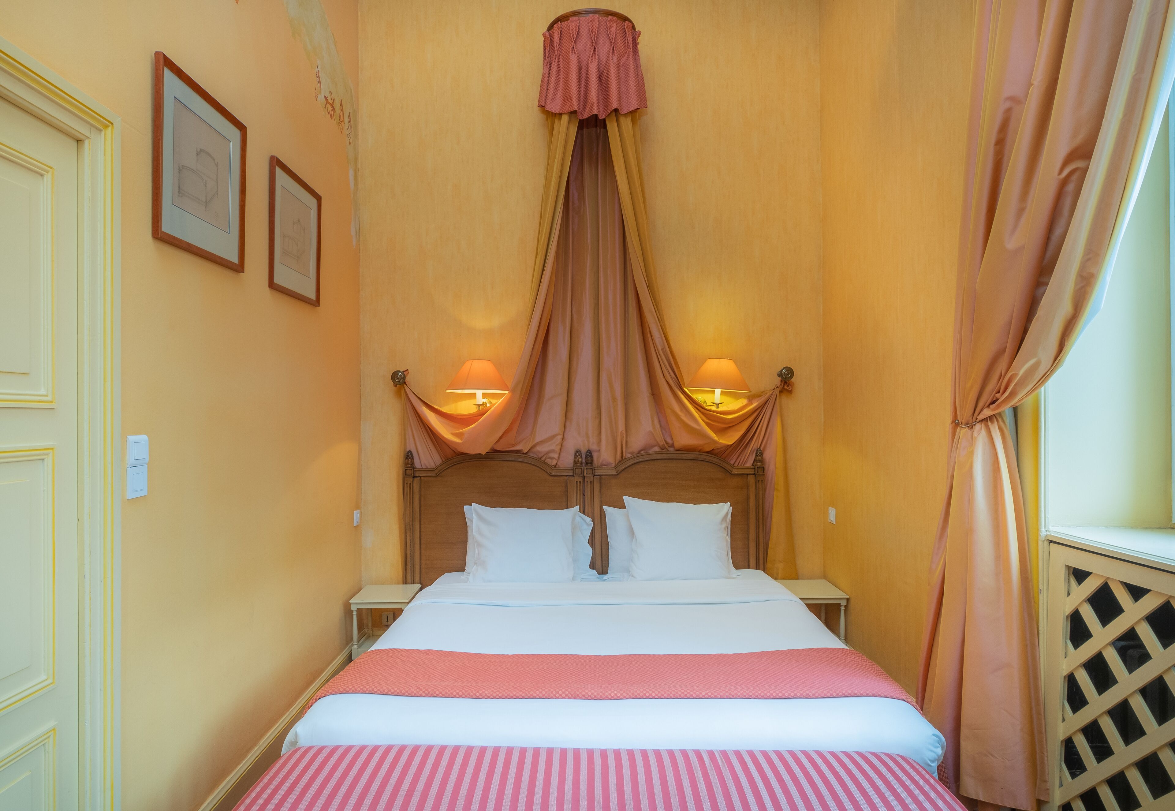 A bed with a canopy, two bedside lamps, and a wooden headboard.