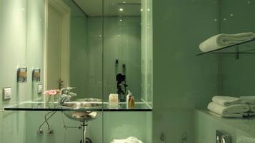 A modern bathroom with a glass sink, a glass shower enclosure, and a towel rack.