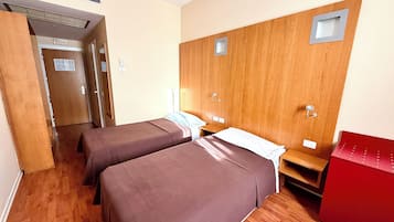 Une chambre d’hôtel avec deux lits, des lambris en bois sur les murs, une armoire rouge et un plancher en bois.