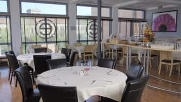 Un espace repas avec des tables rondes, des chaises et un buffet.