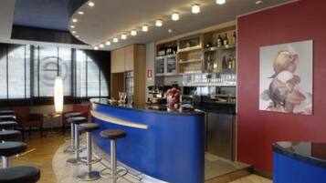 A bar area with stools, a counter, and shelves with bottles.